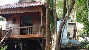 A wooden cabin with a balcony, surrounded by trees. - Rock Sand Hostel (Koh Rong)