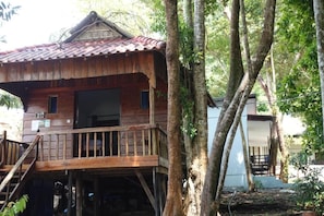 A wooden cabin with a balcony, surrounded by trees. - Rock Sand Hostel (Koh Rong)