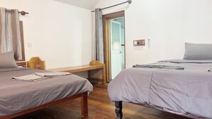 A room with two beds, a wooden bench, a small table, and a door leading to another room. - Rock Sand Hostel (Koh Rong)