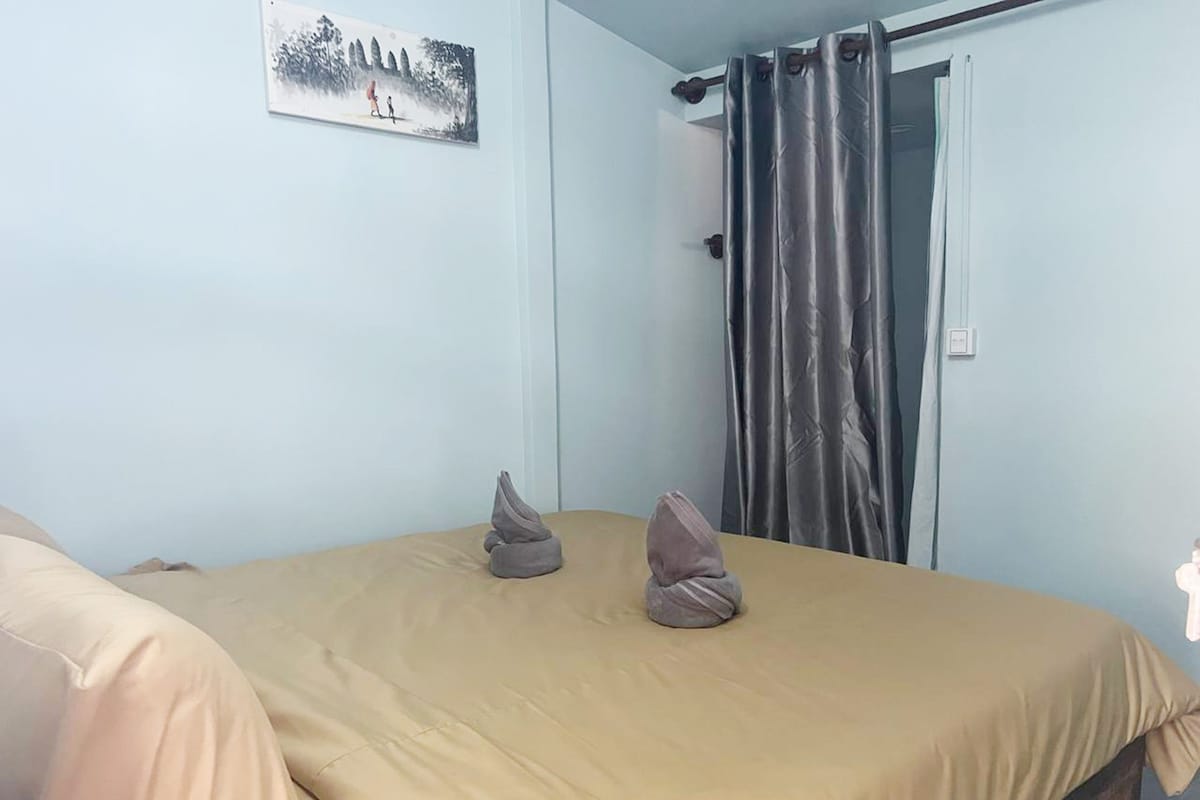 A bedroom with a bed, a door, and a curtain.