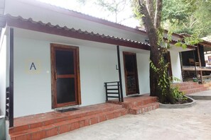 A building with a white exterior, a wooden door, and a brick entrance. - Rock Sand Hostel (Koh Rong)