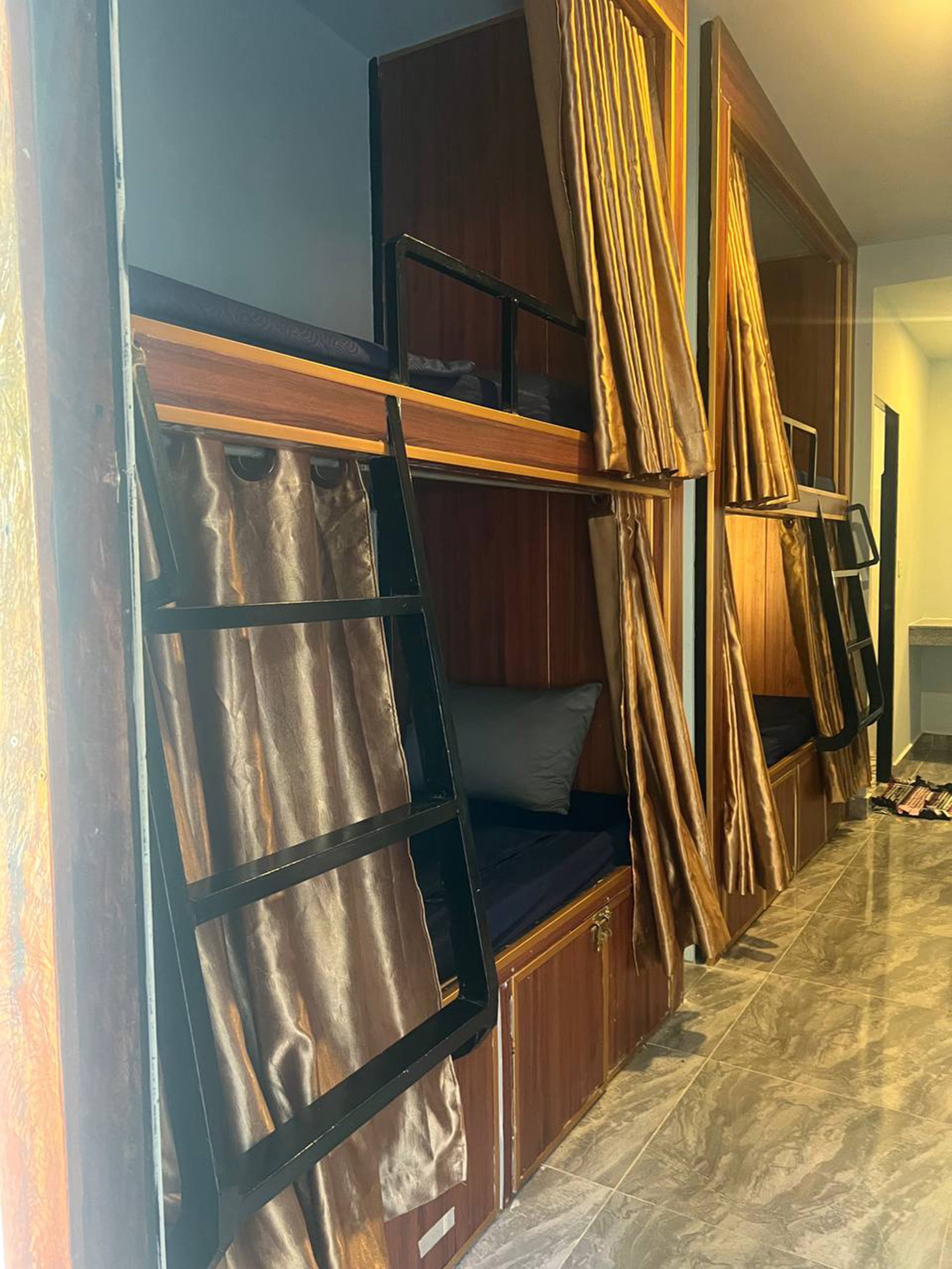 Uma cama box com escada, um guarda-roupa de madeira e uma cortina.