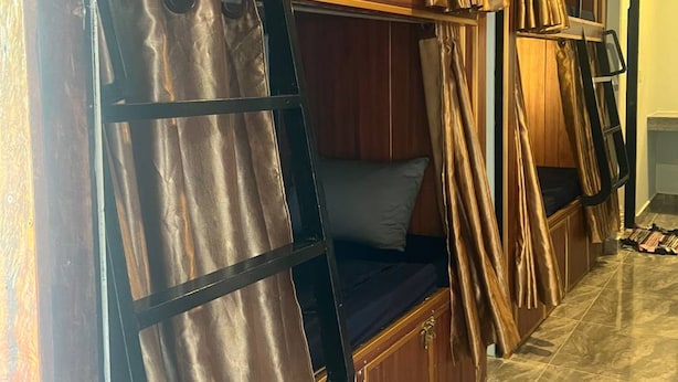A bunk bed with a ladder, a wooden wardrobe, and a curtain.