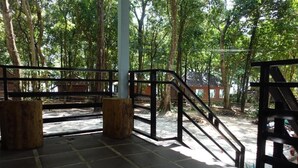 A wooden deck with a metal railing, surrounded by trees.