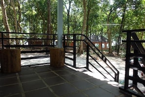 A wooden deck with a metal railing, surrounded by trees.