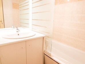 Un baño con lavamanos, espejo y bañera.
