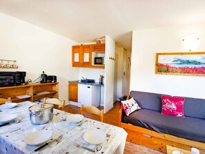 A compact living space with a dining area, kitchenette, and a sofa with a painting. - Bright apartment with valley view - 6 guests (Villarodin-Bourget)