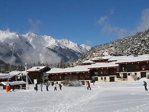 Ein schneebedecktes Bergresort mit Chalets und einer Skipiste.