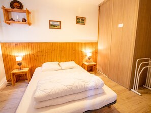 Ein Schlafzimmer mit einem hölzernen Kopfstück, zwei Nachttischen mit Lampen, einem Bett mit weißer Bettwäsche und einem Holzschrank.