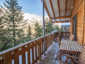 Eine Holzterrasse mit Geländer, einem Holzstapel und einer Bank.