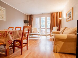 A cozy living room with a dining area, a sofa, and a TV mounted on the wall. - Apartment by the slopes, pets allowed - 8 guests (Villarodin-Bourget)