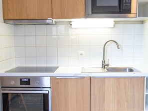 Eine Küche mit Holzschränken, einer Edelstahl-Spüle, einer Mikrowelle und einem Backofen.