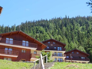 Eine Holzhütte mit Balkonen, eingebettet in einen bewaldeten Hang.