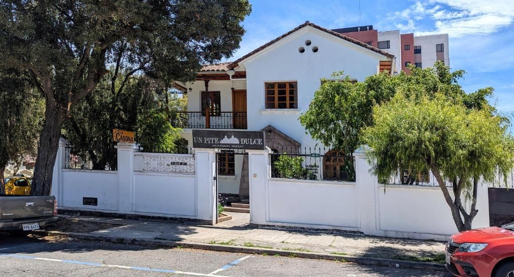 Un edificio de dos pisos con un cartel que dice 'UN PITE DULCE' y una entrada con reja.
