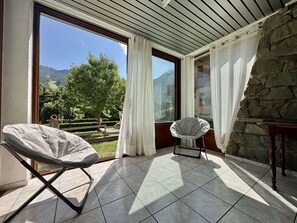 Ein Zimmer mit Blick auf eine gebirgige Landschaft, einer Steinsäule und einem Kachelboden.