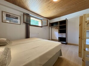 A bedroom with a bed, a wardrobe, a radiator, and a window. - Cozy apartment, 6 guests, peaceful location (La Salle-les-Alpes)