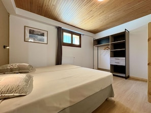 A bedroom with a bed, a wardrobe, a radiator, and a window with curtains. - Cozy apartment, 6 guests, peaceful location (La Salle-les-Alpes)