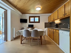 Une cuisine compacte avec des meubles en bois, un lave-vaisselle encastré et un coin repas comprenant une table et des chaises.