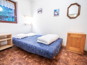 Ein Schlafzimmer mit einem Bett, einem Holzschrank, einem an der Wand befestigten Spiegel und einem Gemälde.