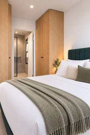 A bedroom with a bed, a bedside table, a nightstand, and a wall-mounted shelf. - The Melbourne Edit. Heated Pool, Gym, Sauna, Steam (Southbank)