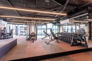A gym with various exercise equipment, large windows, and a modern design. - The Melbourne Edit. Heated Pool, Gym, Sauna, Steam (Southbank)