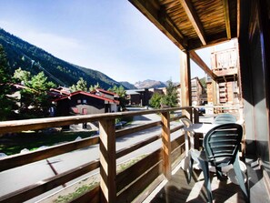 A wooden balcony with a view of a mountain landscape, a road, and buildings. - Practical studio near the slopes - 4 guests (Villarodin-Bourget)