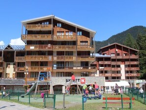 A multi-story building with balconies, a ski lift, and a playground area. - Studio mountain view, pets welcome - 3 guests (Valfréjus)