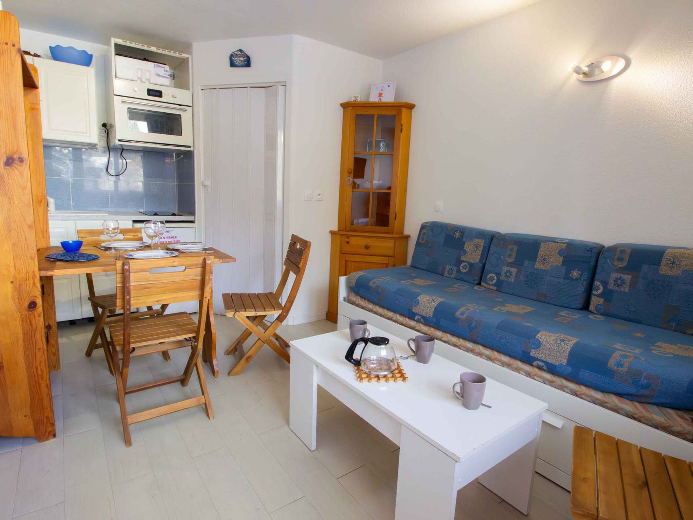 A compact living space with a kitchenette, a dining table with chairs, a sofa, and a coffee table.