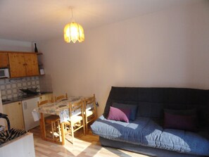 A compact living space with a dining table, chairs, a sofa, and a hanging light fixture. - Apartment mountain view - 4 guests (Villarodin-Bourget)