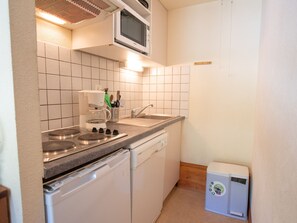 Eine kompakte Küche mit Mikrowelle, Kaffeemaschine, Spüle und Geschirrspüler.