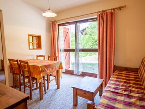 Ein Essbereich mit Tisch und Stühlen, einer Couch und einem Fenster mit Vorhängen.