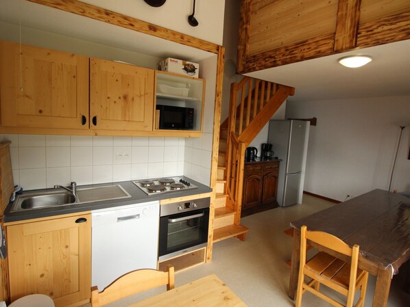 A kitchen with wooden cabinets, a microwave, a stove, and a refrigerator. - Spacious duplex mountain view - 12 guests (Valfréjus)