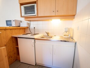 Eine kleine Küche mit Geschirrspüler, Herd, Mikrowelle und Kaffeemaschine.