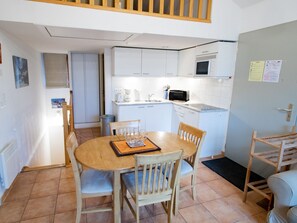 A compact kitchen with white cabinets, a microwave, and a dining area with a wooden table and chairs. - Half-chalet, WiFi, pets welcome - 6 guests. Mountain view (Villarodin-Bourget)