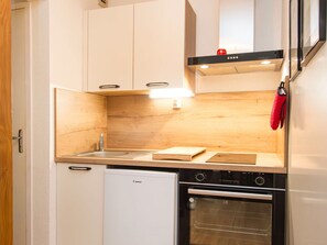 A compact kitchen with a built-in dishwasher, oven, and a wooden backsplash. - 2-room apartment with balcony - 4 guests (Villarodin-Bourget)