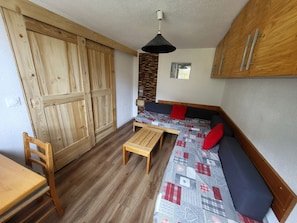 A compact living space with a wooden wardrobe, a bench, a table, and a sofa with patterned upholstery. - Welcoming apartment, pets OK - 8 guests - Slope view (Villarodin-Bourget)