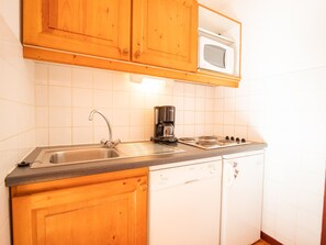Eine Küche mit Holzausstattung, einer Mikrowelle, einer Kaffeemaschine, einem Spülbecken und einem Geschirrspüler.