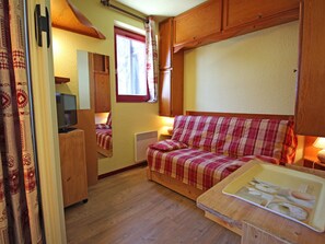 A compact RV interior with a kitchenette, a bed, and a television. - Charming apartment, mountain view - 4 guests (Villarodin-Bourget)