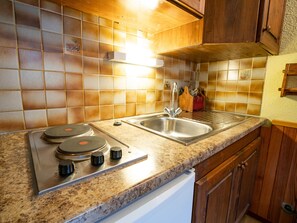 A kitchen with a stainless steel sink, a double electric stove, and wooden cabinets. - Charming apartment, mountain view - 4 guests (Villarodin-Bourget)