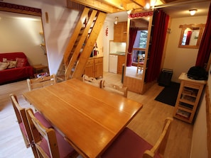 A compact living space with a wooden dining table, chairs, a sofa, a kitchen area, and a staircase. - Lovely quiet apartment - 8 guests (Villarodin-Bourget)