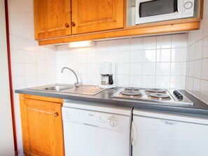 A kitchen with wooden cabinets, a microwave, a coffee maker, a sink, and a dishwasher. - Studio cabin mountain view - 4 guests (Valfréjus)
