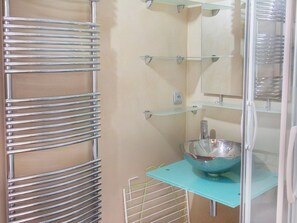 Ein Badezimmer mit einer Duschkabine aus Glas, einem Metallhandtuchhalter und einem Waschbecken mit Schüssel.