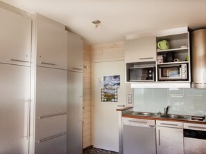 Eine kleine Küche mit Kühlschrank, Mikrowelle, Backofen und Geschirrspüler.