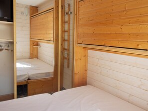 Ein Zimmer mit einem Etagenbett, einer Stehleiter und einer Holzwand.