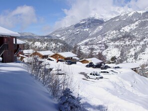 Une station de montagne enneigée, avec des chalets en bois et un télésiège.