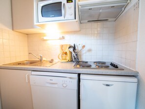 Eine kleine Küche mit Mikrowelle, Kaffeemaschine, Herd, Spüle und Geschirrspüler.