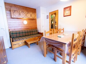 Ein Holzespeisesaal mit Stühlen, eine Bank mit Karomusterbezug und ein Holzschrank mit Leuchte darüber.