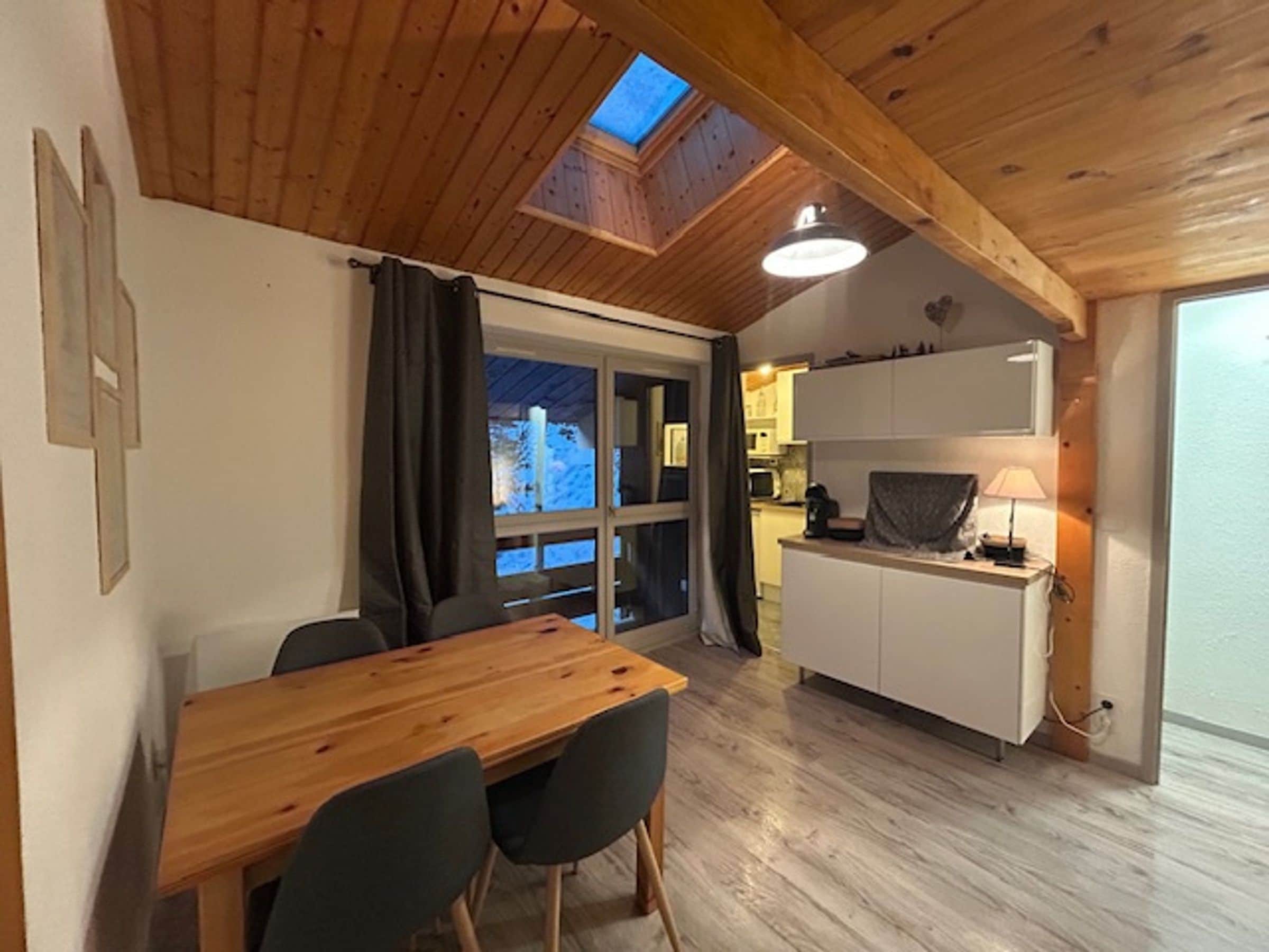 A wooden interior with a dining area, a kitchen, and a skylight.