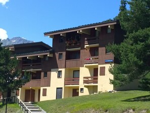 A multi-story building with balconies, a sign indicating 'LES CAMPANILLES,' and a mountain in the background. - Renovated apartment - 7 guests, forest edge (Villarodin-Bourget)