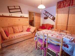 Ein gemütlicher Holzraum mit einer Couch, einem Esstisch mit Stühlen und einer Holzleiter an der Wand.